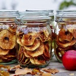 Torkade äppelringar i glasburkar med höstlöv och äppleringar bredvid